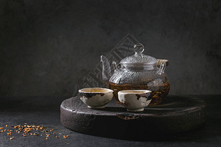 热绿茶在两个传统的中国粘土陶瓷杯和玻璃茶壶站在托盘上的黑色大理石桌子.