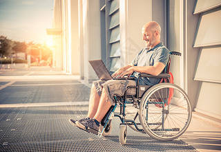 Man on wheel chair using computer