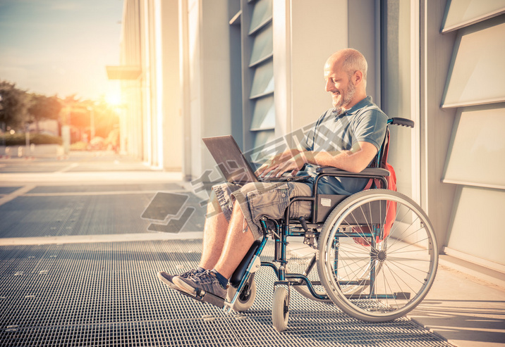 Man on wheel chair using computer