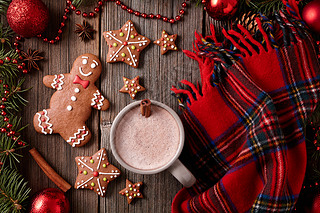 Cup of hot chocolate or cocoa with gingerbread cookies and warm scarf composition in fur tree decora