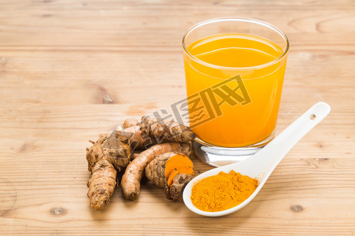 Healthy turmeric roots drinks in a transparent glass on wooden s