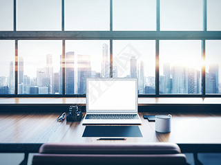 Photo of laptop on the worksplace with panoramic windows.  City at sunrise in a background. 3D rende