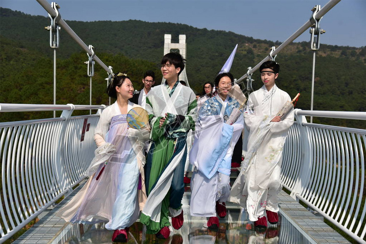 Models dressed in Hanfu or traditional Chinese costume pose on a glass-bottomed bridge in Foshan cit