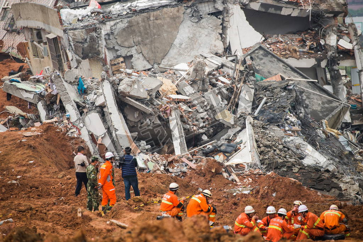 Chinese rescuers rest on the debris of a collapsed building at the site of the landslide, which hit 