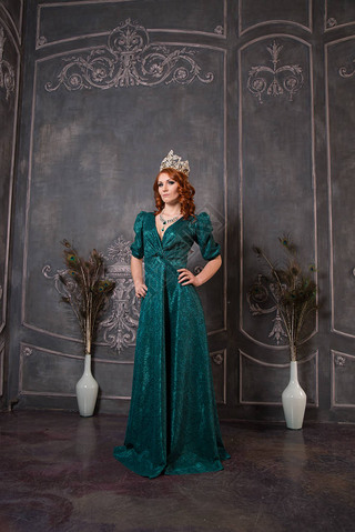 Gorgeous young woman in luxury dress and diamond crown posing in vintage room