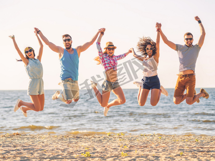 happy young people jumping on beach