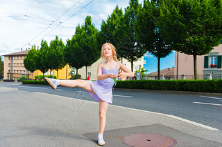 Outdoor portrait of a cute little girl of 7 years old, walking to dance school and dancing in the st