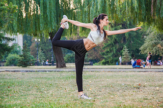 Young happy beautiful y girl is stretching in the park garden. people background. with dark hair