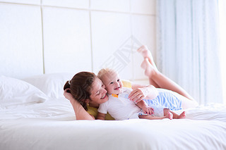 Mother and baby relaxing in white bedroom