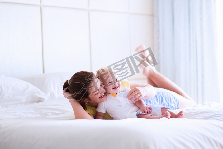 Mother and baby relaxing in white bedroom