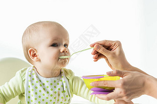 Mother feeding baby son with baby nutrition on white background