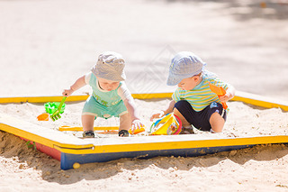 Two baby boys playing with sand