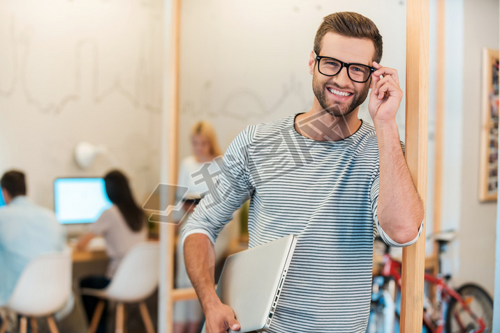 man carrying laptop and adjusting his eyeglasses