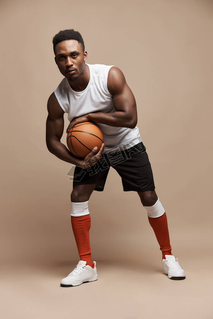 full length photo of a dark-skinned athletic basketball player in studio on a beige background posin