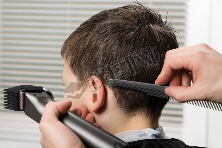 cut hair to the boy using a clipper and comb ////