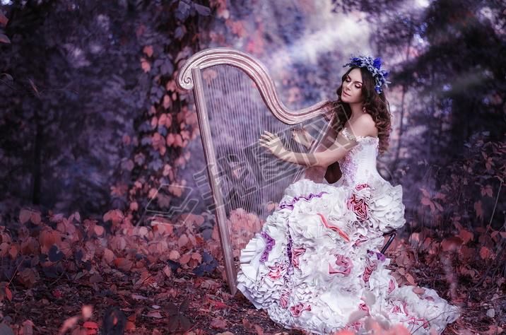 beautiful brown-haired woman with a flower wreath on her head, wearing a white dress playing the har