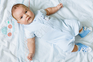 Portrait of a pretty little baby , lying on a light blanke