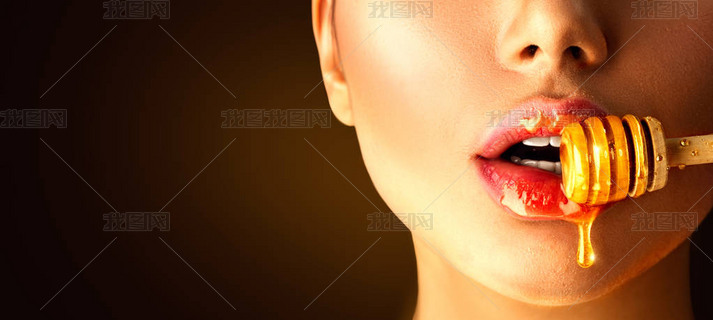蜂蜜从木勺滴在性感的女人嘴唇上。美女模特 女人 吃 蜂蜜