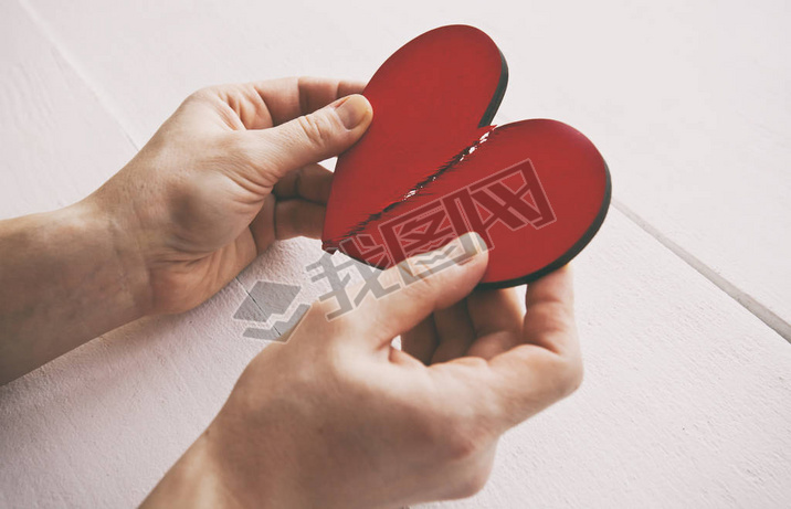 The broken red wooden heart in woman's hands