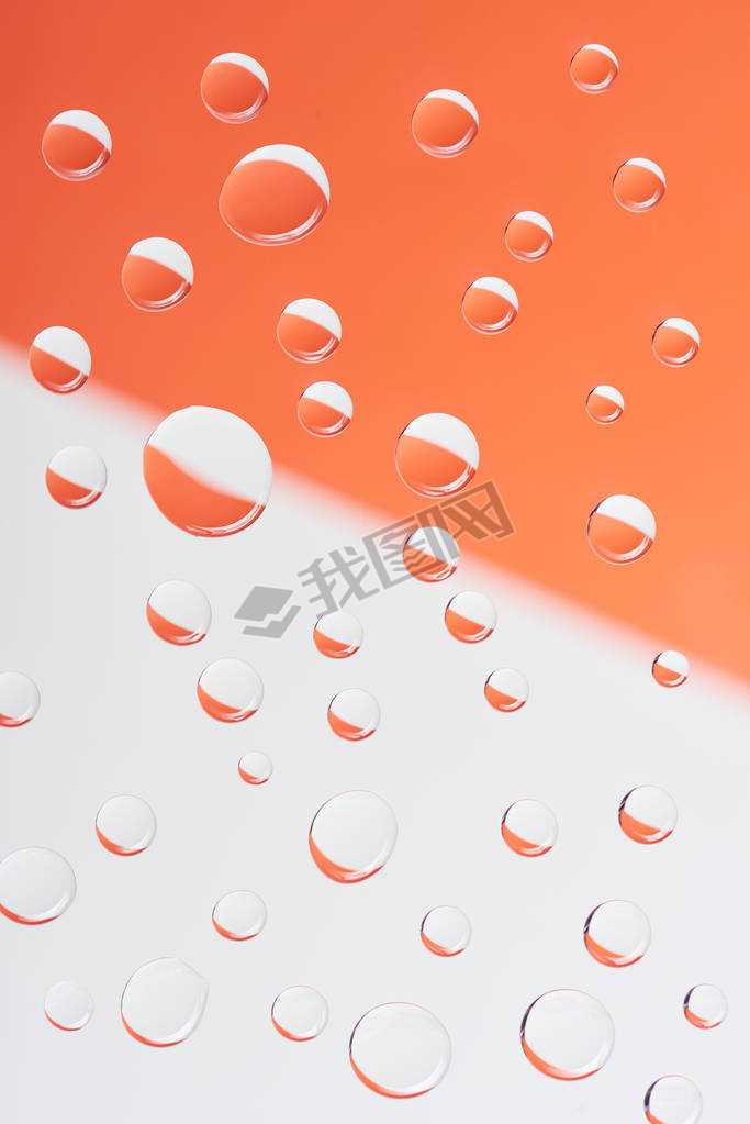 close-up view of transparent calm water drops on white and orange background          