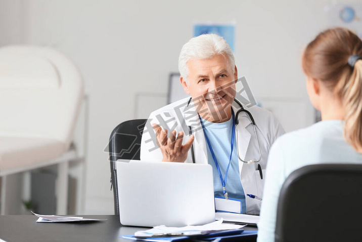 Mature male doctor working with patient in clinic