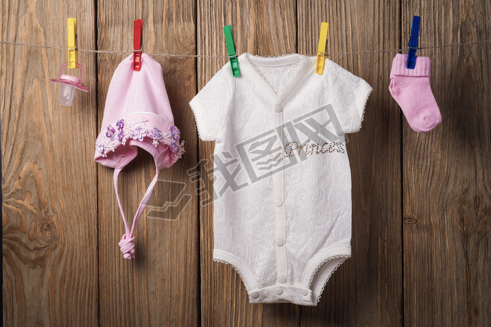 Baby clothing hanging on the clothesline on a wood background