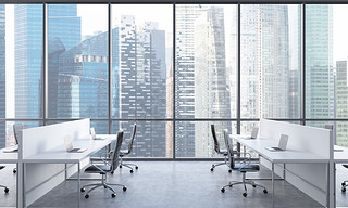 Workplaces in a bright modern open space office. White tables equipped with modern laptops and black