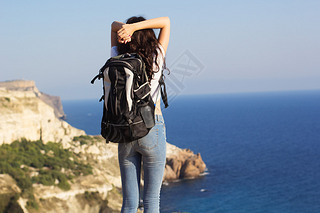 Back view of treler is standing on rock with backpack