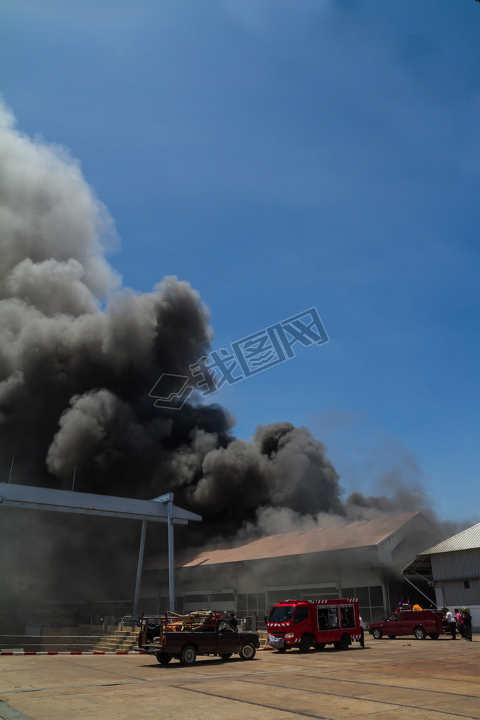 Burning warehouses with black oke against blue sky