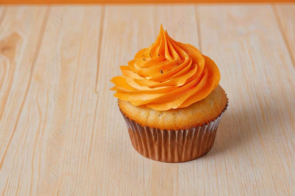 原创木桌上有橙色糖霜的纸杯蛋糕图片
