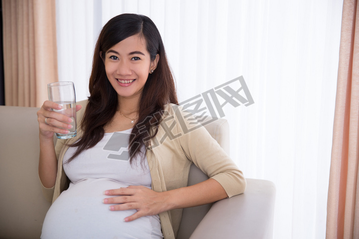 Pregnant asian woman drinking a glass of water