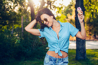young beautiful short blue hair hipster woman with headphones music in the park. ice cream