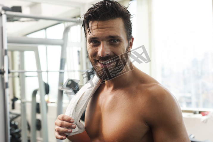 Young strong fit man iling, exercising in the gym