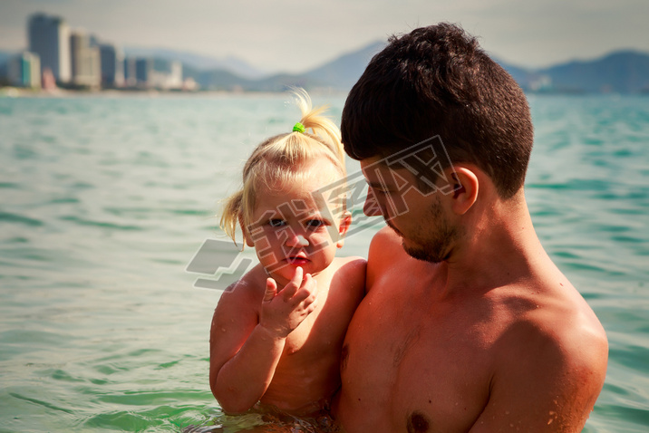 european young father holds iling little daughter in shallow s
