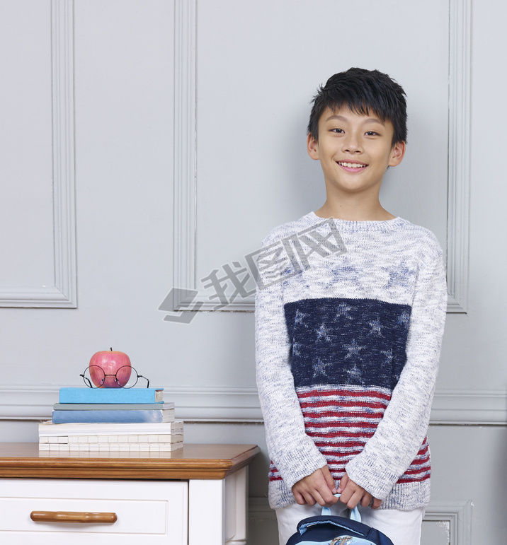 young asian boy iling standing beside book desk