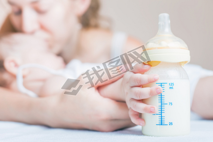 Baby holding a baby bottle with breast milk