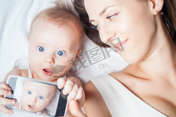 Funny baby girl with mom make selfie on mobile phone