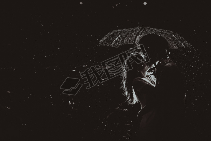 Dramatic photo of a bride and groom in the night rain.