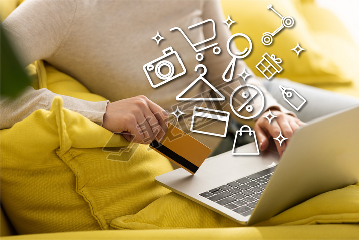 Cropped view of woman holding credit card and using laptop near illustration