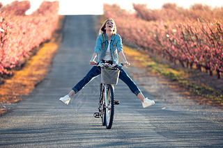 Pretty young woman with a vintage bike enjoying the time in cherry field in springtime.