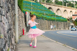 Outdoor portrait of a cute little girl of 7 years old, walking to dance school and dancing in the st