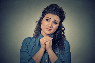 young woman gesturing with clasped hands, please forgive me