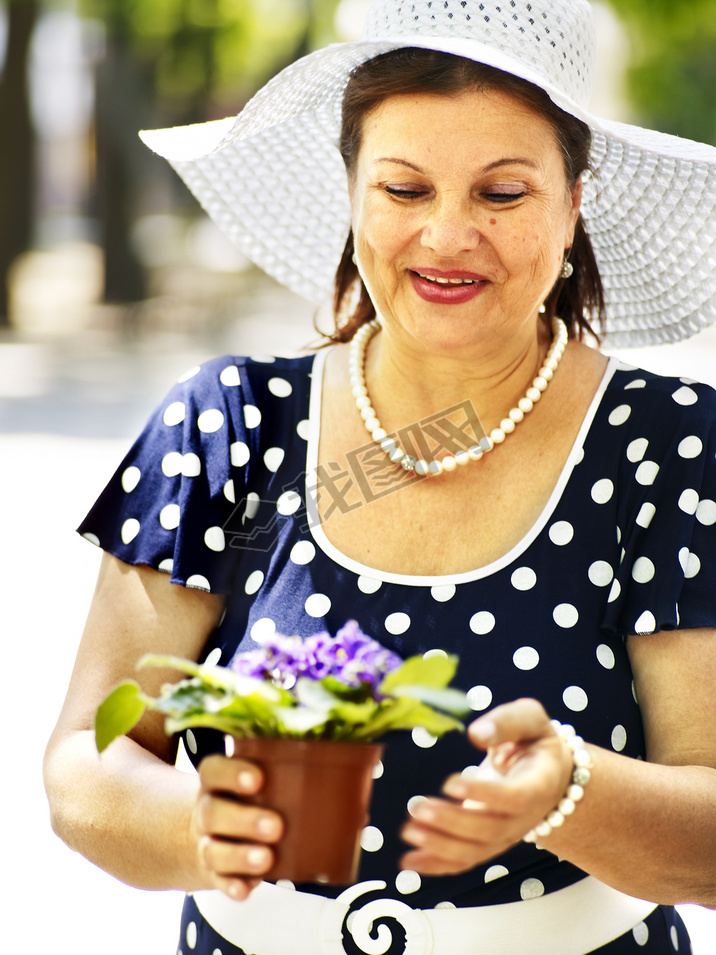 glad gammal kvinna med blomma utomhusֵŮ뻨.