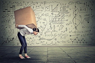 woman carrying hey box walking along gray wall