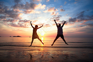 Concept of long-awaited vacation: Young couple in a jump on the sea beach at sunset.