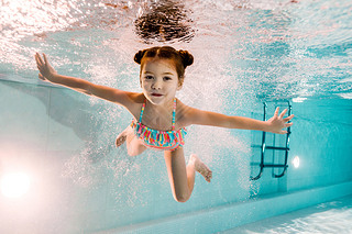 adorable kid swimming underwater in blue water in swimming pool