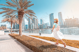 Happy asian girl walking on a promenade in Dubai Marina district. Trel and lifestyle in United Ara