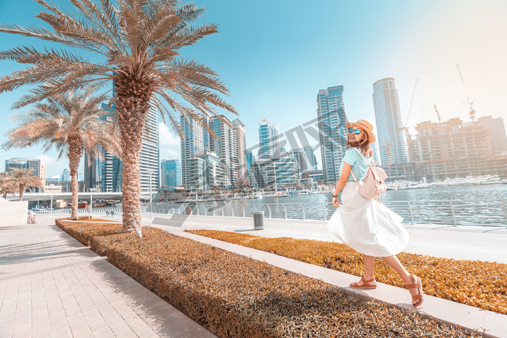 Happy asian girl walking on a promenade in Dubai Marina district. Trel and lifestyle in United Ara