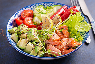 Healthy grilled salmon, ocado, tomato, cucumber, paprika and chia seeds. Balanced lunch in blue bo