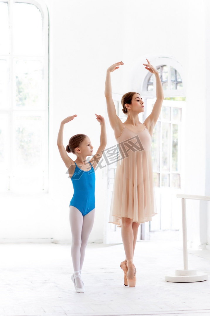 The little ballerina posing at ballet barre with personal teacher in dance studio